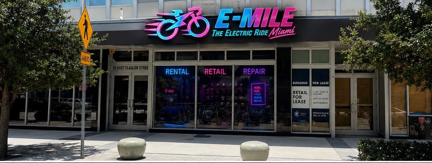 Neon-lit E-MILE electric ride storefront in Miami featuring rental, retail, and repair services.